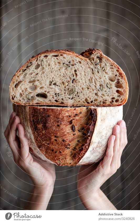 Erntehelfer mit halbiertem Saatgutbrot Person Brot frisch Samen Hälfte zeigen Mahlzeit Lebensmittel Wand Küche heimwärts Snack rustikal gebacken lecker