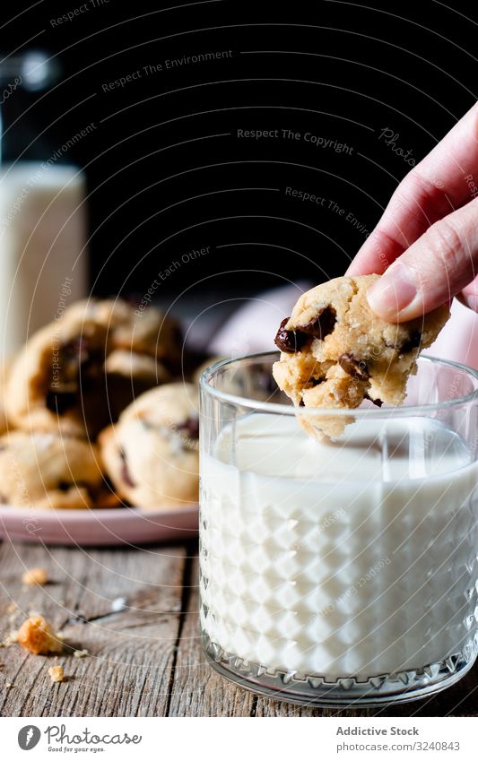 Nutzpflanzenfrau taucht veganen Keks mit Schokosplittern in Milch Frau melken Dip Veganer Schokolade Chip Spielfigur Glas heimwärts trinken Getränk Lebensmittel