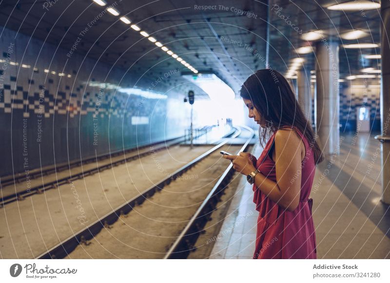 Langhaarige Frau mit Smartphone vor U-Bahn-Wagen stehend Warten benutzend stoppen urban Podest unterirdisch Browsen Surfen Budapest Ungarn Apparatur Gerät