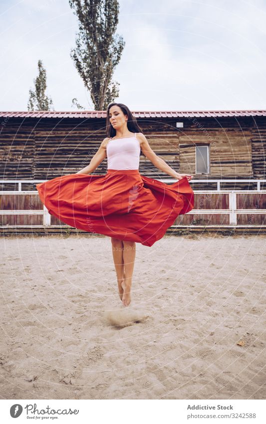 Frau in buntem Rock tanzt auf ländlicher Koppel Tanzen Sattelkammer farbenfroh rot künstlerisch springen Sand Gehege Scheune Bauernhof Tageslicht jung