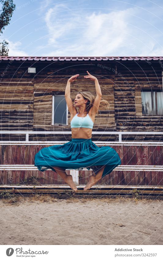 Flexible Frau im bunten Rock tanzt auf ländlicher Koppel Tanzen Sattelkammer künstlerisch springen Sand Biegen beweglich Gleichgewicht lang Gehege farbenfroh