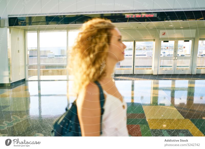 Nachdenkliche Frau geht in geräumiger Halle im Sonnenlicht Saal Flughafen Innenbereich Murmel Glas modern Wandelhalle Design reisen Glanz Gate international
