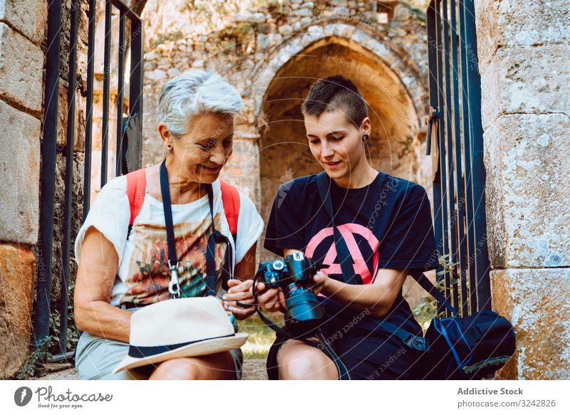 Stilvolle junge Frau zeigt reifer Dame auf steinigen Stufen Fotografie Frauen zuschauend Fotokamera Urlaub Sommer Fotografieren Gedächtnis Großmutter Enkelin