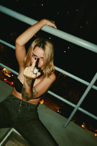 Frau mit Mittelfinger auf dem Balkon obszön sexy gestikulieren anstößig Jeanshose vulgär provokant jung erotisch Bauch Dame Würzig verführen sexuell ficken