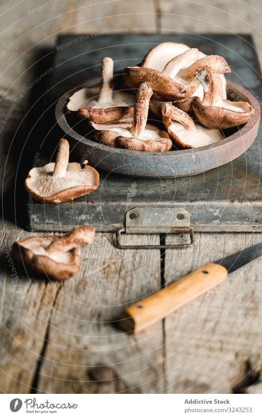 Haufen frischer brauner Champignons auf rustikalem Holztisch Pilz Bestandteil Messer Küche Essen zubereiten Ernährung Shiitake Lebensmittel Mahlzeit kultiviert
