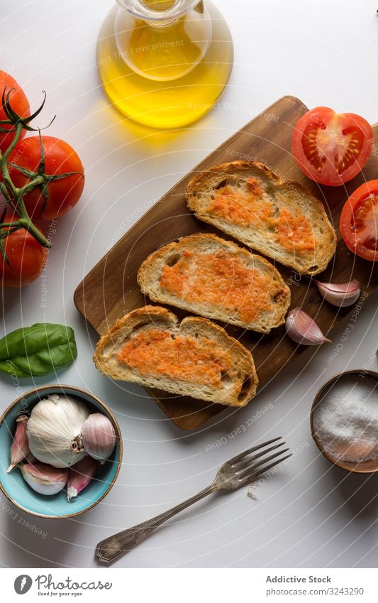 Gewürze und Gemüse in der Nähe von Toast Zuprosten Saucen Bestandteil Tomate Salz Knoblauch Basilikum Erdöl Brot Schneidebrett Tisch Lebensmittel Snack lecker