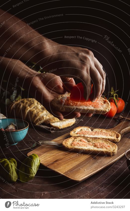 Erntehelfer, der Tomaten auf Toast gießt Person Zuprosten Koch eingießen Erdöl Brot Saucen Lebensmittel Speise lecker geschmackvoll frisch Spielfigur Scheibe