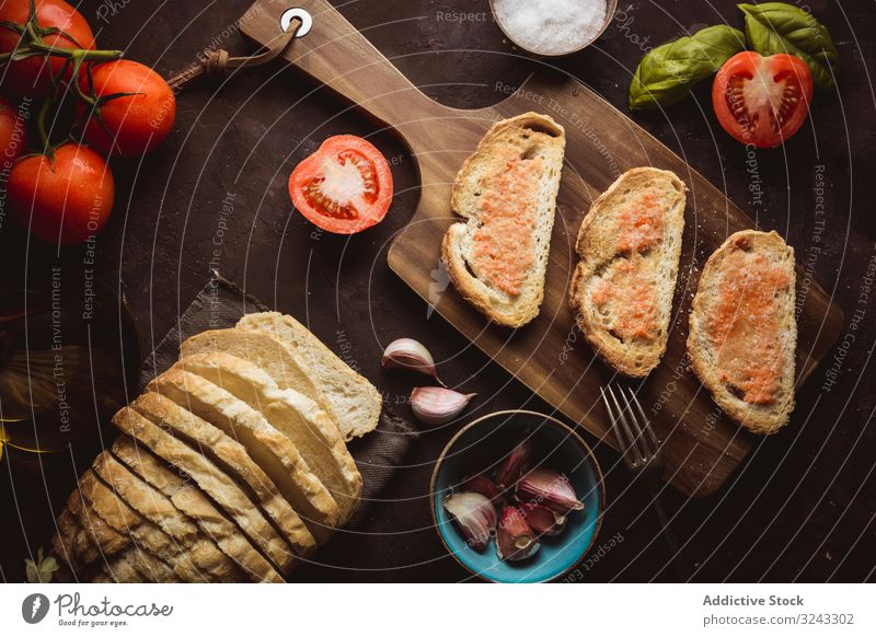 Gewürze und Gemüse in der Nähe von Toast Zuprosten Saucen Bestandteil Tomate Salz Knoblauch Basilikum Erdöl Brot Schneidebrett Tisch Lebensmittel Snack lecker