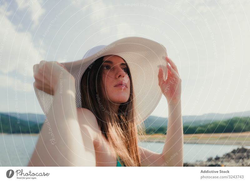 Junge Frau mit Hut ruht sich am Strand aus See ruhen Sommer jung verträumt wolkig Himmel Wasser Urlaub Wochenende Lifestyle Natur Landschaft Kopfbedeckung