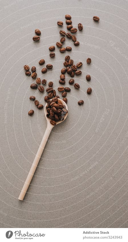 Kaffeebohnen im Löffel auf grauer Oberfläche Bohne gebraten dunkel Streuung Geschmack Baggerlöffel Feinschmecker Tisch Korn Aroma braun einfach natürlich