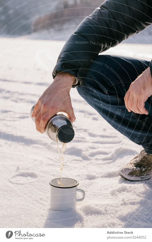 Mann gießt am Wintertag Tee aus Thermosflasche Thermoskanne Schnee eingießen Sibirien Natur kalt Aufwärmen Russland männlich sitzen heiß Pause Flasche ruhen