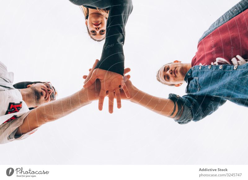 Gruppe junger Menschen, die sich die Hände reichen Setzen Stapelung Zusammensein Teamwork Einheit Menschengruppe Pflege Erfolg teilnehmen Interaktion selbstlos