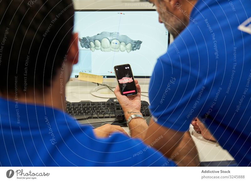 Anonyme Kieferorthopäden vergleichen Dentalmodelle im Labor 3d Zahnmodell Computer untersuchen Monitor Smartphone Männer Zähne Hallo Technik Maschinenbau Arzt