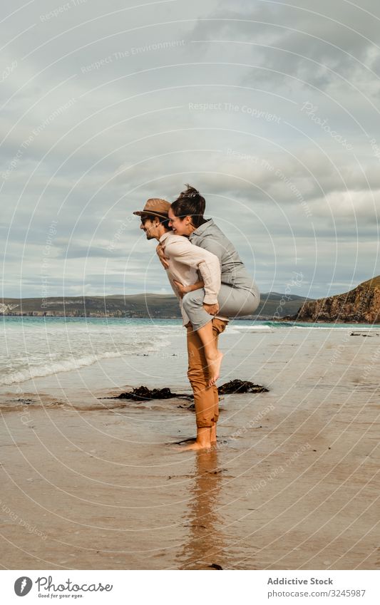 Glückliches Paar amüsiert sich an der schottischen Küste Spaß Strand sandig Felsen Schottland Schottisch wolkig Zusammensein genießen Beteiligung Huckepack