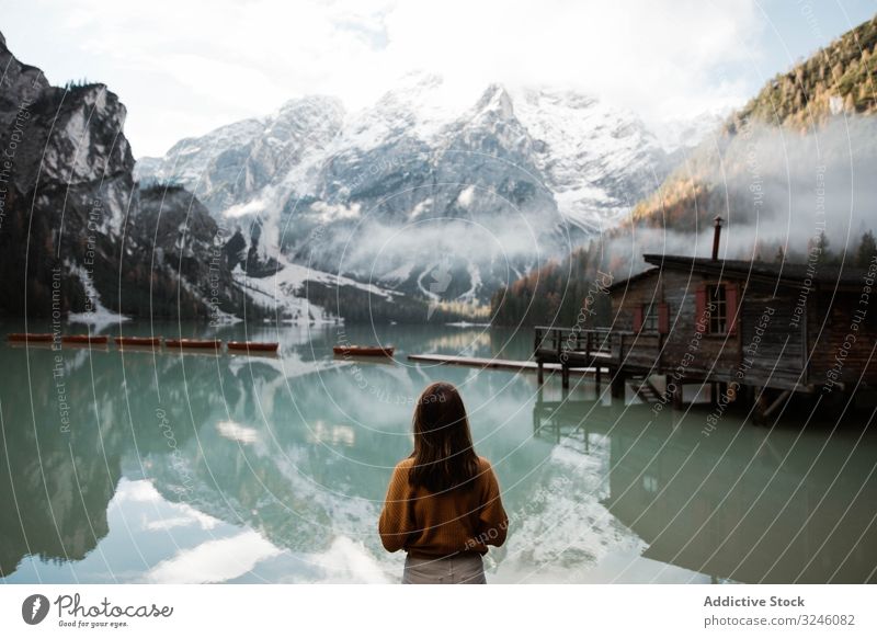 Ruhende Frau in Freizeitkleidung, die sich an Aussichten in der Nähe von See und Bergen erfreut Tourismus Haus Wasser Boot Nebel wolkig reisen Landschaft Urlaub