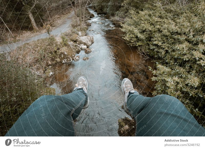 Tourist sitzt auf Brücke und baumelt mit den Beinen über den Fluss baumelnd hängen Wald sitzen Republik Irland Park mautmehr Wanderer Person aktiv Spaziergang