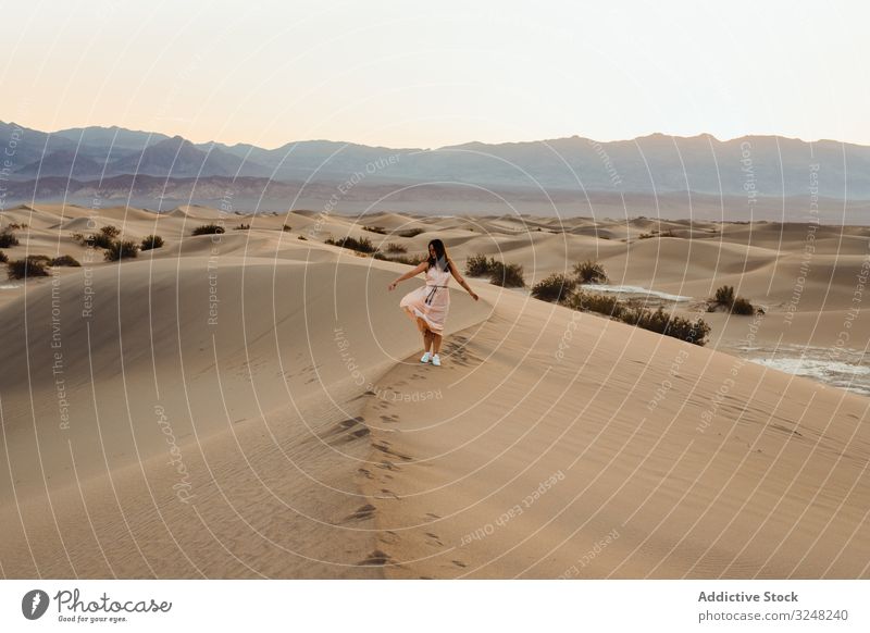 Rückenansicht einer jungen Frau, die in der Wüste wandert und in den trockenen Sanddünen im Death Valley Fußspuren hinterlässt laufen Tal des Todes Fernweh wüst