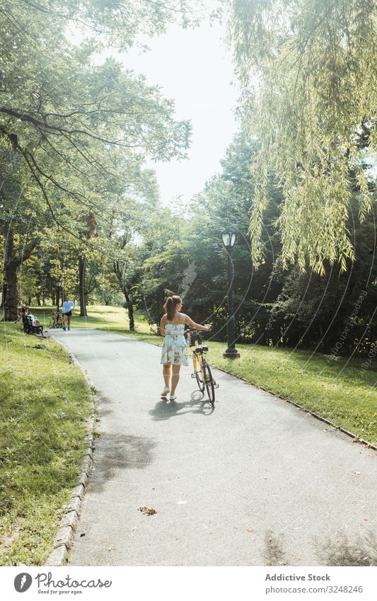 Lässig fahrendes Damenfahrrad im schönen Park Frau wheeling Fahrrad laufen Sommer Sonnenlicht lässig Kleid Aktivität Lifestyle Sport Straße Verkehr Wochenende