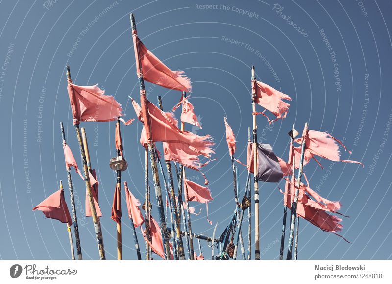 Zerklüftete Fischereimarkierungsflaggen gegen den blauen Himmel. Wolkenloser Himmel Wind Fahne alt stachelig rot Beratung Fischen Markierung Instagrammeffekt