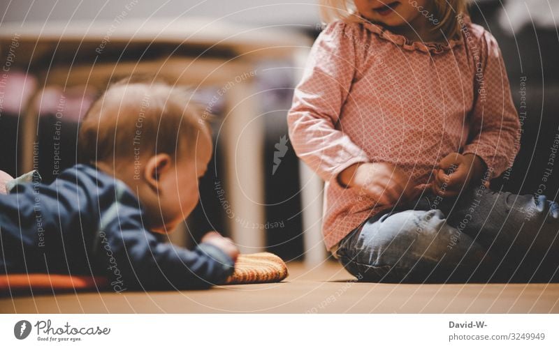 Kinder spielen zusammen auf dem Boden spielend Spielen Mädchen Junge Kindheit Geschwister Bruder Schwester beschäftigen ärgern necken Geschwisterkind klein