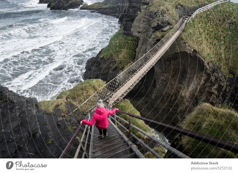 Frau überquert Seilbrücke zur Felseninsel Brücke MEER Insel Spaziergang Meer Nordirland durchkreuzen Küste carric a red Ufer Wasser Landschaft Selbstvertrauen