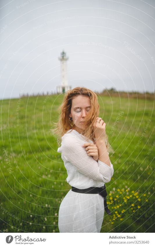 Zärtliche Frau im grünen Feld mit Leuchtturm Angebot Wiese sanft charmant Windstille friedlich Rotschopf Ingwer malerisch Natur Asturien Spanien Europa sinnlich