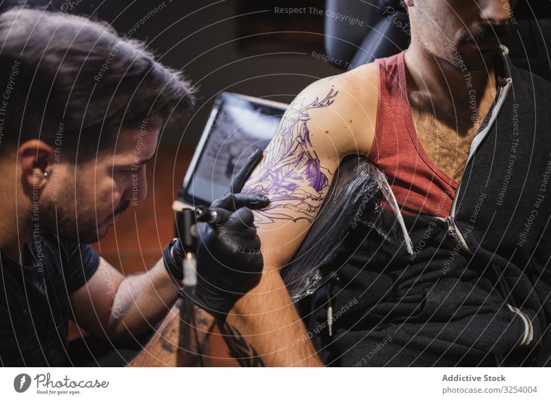 Meister tätowiert Unterarm eines männlichen Kunden Maschine Tattoo Skizze Gerät Werkzeug Instrument kreativ Kunst Pigment Nadel konzentriert fokussiert
