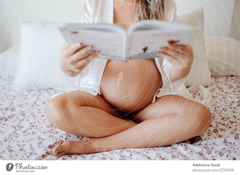 Schwangere Frau liest zu Hause ein Buch Schwangerschaft lesen heimwärts Mutterschaft sitzen Baby Bauch Gesundheit jung erwarten Pflege Lifestyle pränatal Eltern