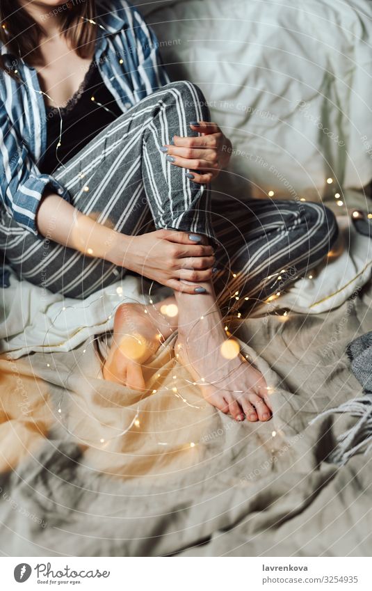 Frau sitzt in ihrem Bett mit weihnachtlichen Lichterketten. Abend gemütlich Feste & Feiern Feiertag gesichtslos Pyjama Weihnachten & Advent Hygge Unschärfe