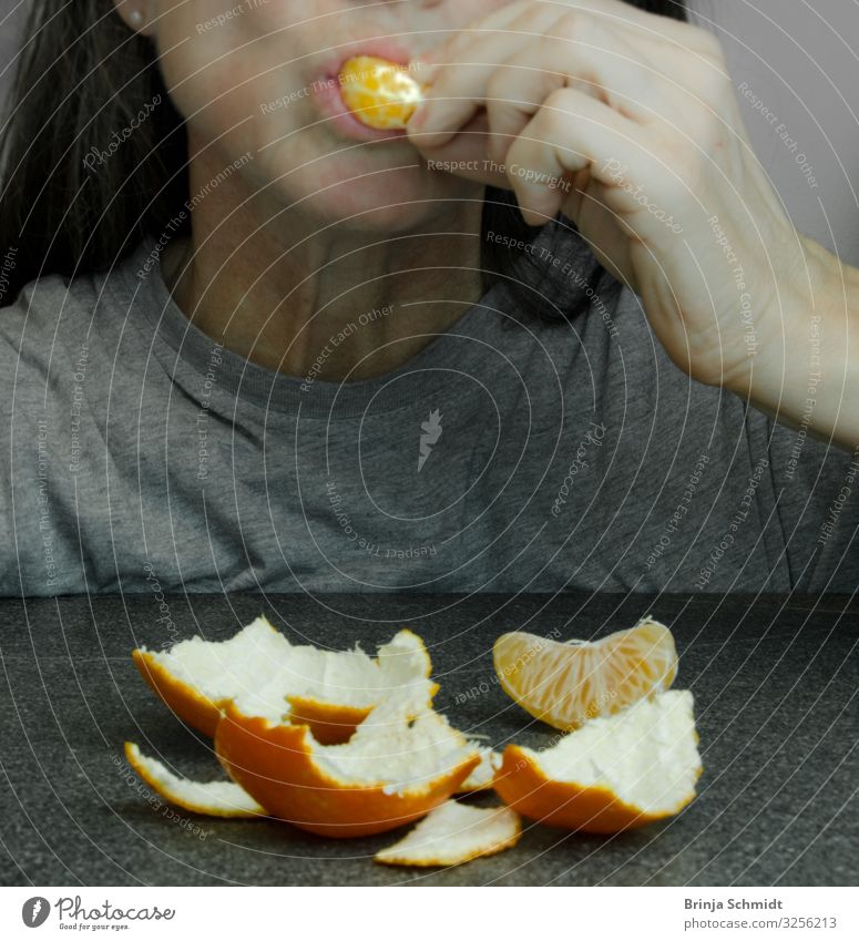 Eine Frau schiebt sich ein Stück Mandarine in den Mund Frucht Hülle Zirusfrucht Essen Vegetarische Ernährung Fingerfood feminin Erwachsene genießen leuchten