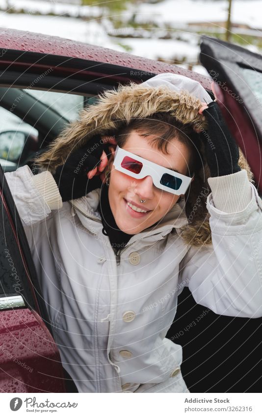 Lächelnde Person, die im Winter aus dem Auto schaut 3D-Brille PKW heraussehen Schnee Piercing Kapuze Armwärmer spielen heiter Stimmung charismatisch Inhalt