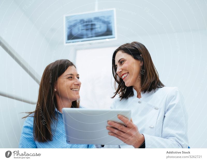 Zahnarzt spricht mit Klient und zeigt Dokument mit Informationen Arzt Stomatologie Besprechung Behandlung Kabinett Gesundheit Zahnschmerzen Medizin Diagnostik