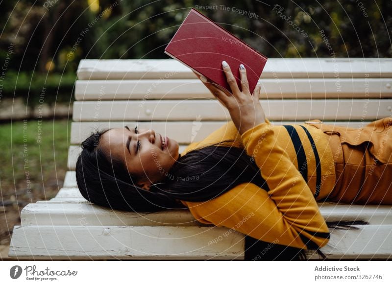 Anmutige langhaarige Asiatin liest Buch auf Parkbank Frau lesen stylisch Bank weiß Mode Model elegant asiatisch klug trendy Dame modisch brünett lernen