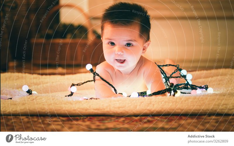 Baby spielt mit Lichtergirlande am Weihnachtstag spielen Weihnachten Girlande farbenfroh gemütlich Abend Vorabend Teppich Stock niedlich bezaubernd Kind Glück
