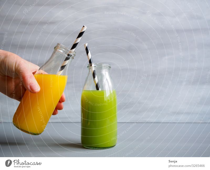 Hand mit Orangensaft und grünen Smoothie Frühstück Diät Getränk Saft Flasche Glas Lifestyle Gesundheit Wellness Leben Wohlgefühl feminin Frau Erwachsene Finger