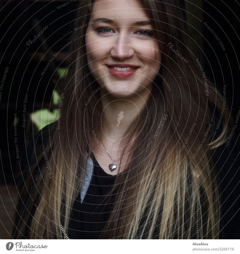 Portrait einer jungen Frau die lächelt und vor dunklem Hintergrund steht Stil Freude schön Leben Wohlgefühl Scheune Junge Frau Jugendliche Gesicht 18-30 Jahre