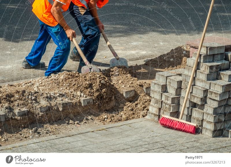 Zwei Bauarbeiter schieben gemeinsam Sand in eine Baugrube - Teamwork Konzept Arbeit & Erwerbstätigkeit Beruf Baustelle Mensch maskulin 2 Bürgersteig