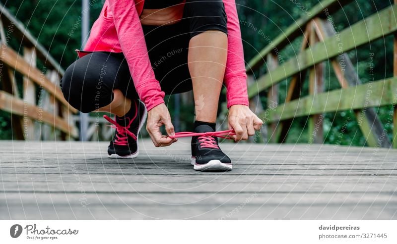 Sportlerin beim Schnürsenkelbinden im Freien Lifestyle Mensch Frau Erwachsene Park Krawatte Schuhe Turnschuh Fitness rosa schwarz Energie unkenntlich Athlet