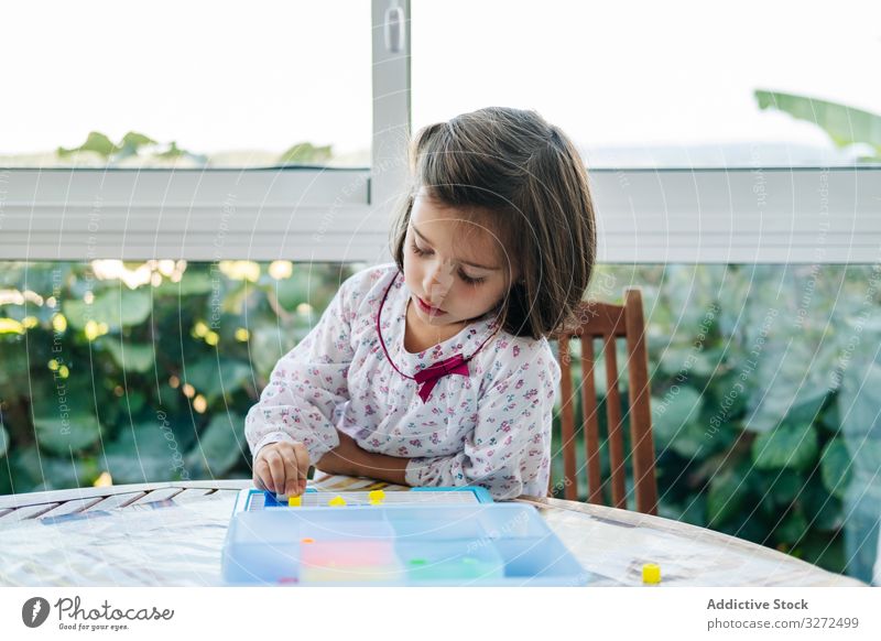 Mädchen spielt mit Mosaik-Brettspiel spielen Spiel Holzplatte kreativ fokussiert Konzentration Spielfigur farbenfroh Bildung Geduldsspiel versammeln Spaß Kind