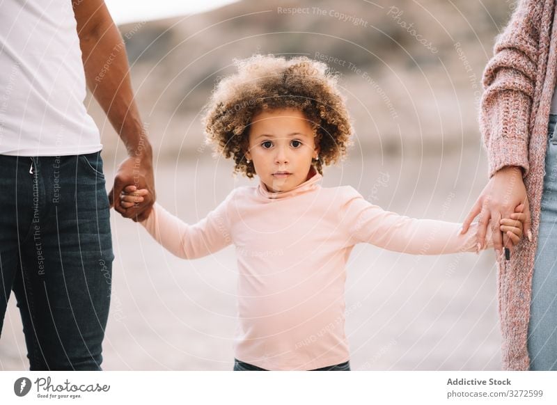 Stilvolle multiethnische Familie geht in der Natur spazieren Spaziergang Hand in Hand Zusammensein Eltern Kleinkind Lächeln Glück schlendern heiter Lifestyle