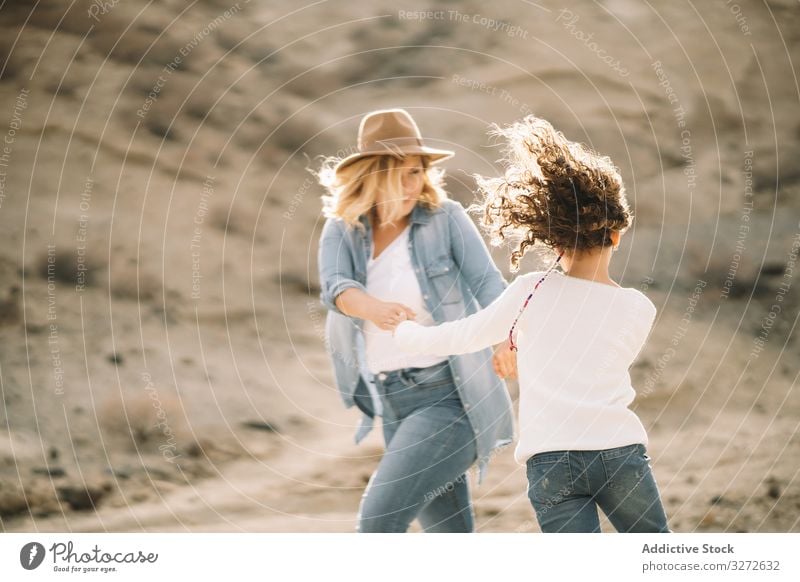 Mutter tanzt mit Mädchen auf der Natur spinnen Eltern Spaß Tanzen Urlaub Tochter Glück Lächeln Sand wüst Spaziergang heiter Lifestyle modern Kind Bonden Liebe