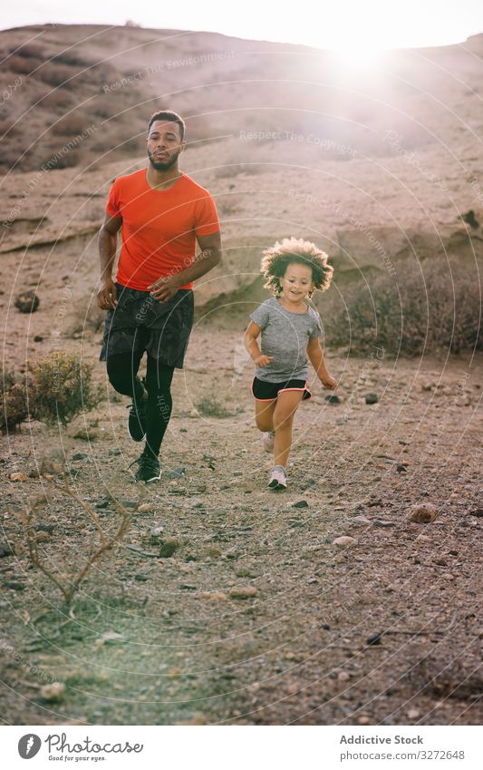 Schwarzer Mann joggt mit Kleinkind in der Natur Kind laufen Joggen Zusammensein Sport aktiv Gesundheitswesen Vater Eltern Lächeln wüst Morgen Lifestyle