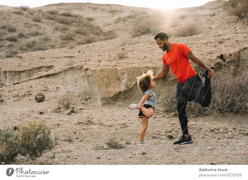 Schwarzer Vater bereitet sich mit Kind auf Sporttraining vor Training Kleinkind Dehnung vorbereiten Aufwärmen Oberschenkel lehren Sportkleidung Mann
