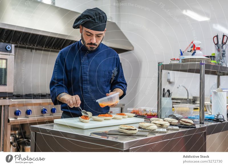 Männlicher Koch bei der Zubereitung von Snacks in der Küche Küchenchef Arbeit Belegtes Brot Kaviar Feinschmecker Abfertigungsschalter Mann vorbereiten Uniform