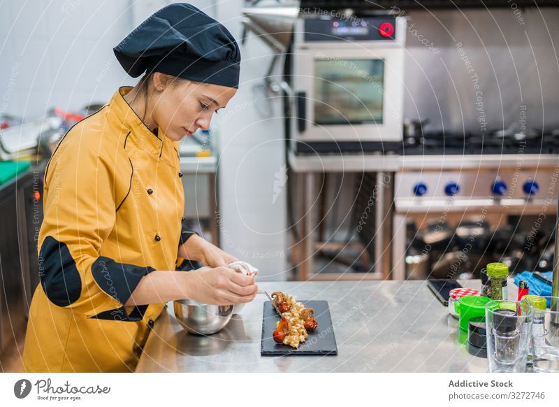 Professioneller Koch garniert Gericht in der Küche Küchenchef Arbeit Frau Garnierung Speise Teller Abfertigungsschalter professionell dienen vorbereiten