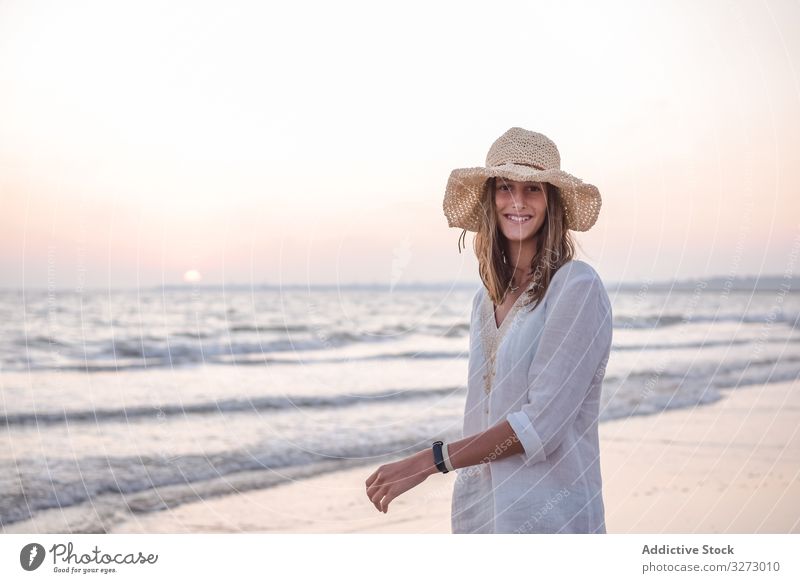Charmante Frau in leichtem weißen Kleid am gewellten Strand MEER reisend Seeküste Tourismus charmant Urlaub Hut lockig Feiertag Sommer Freiheit Reise jung