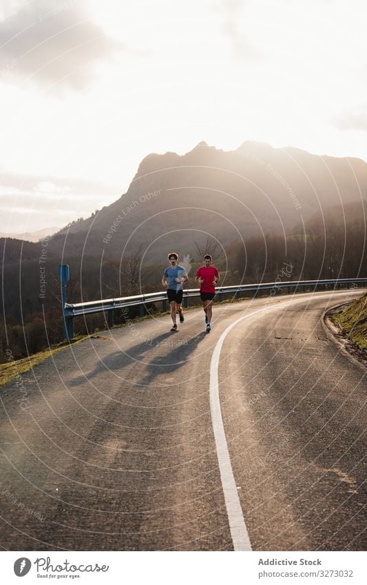 Sportler laufen auf Asphaltstrasse in den Bergen Männer Straße Berge u. Gebirge sportlich Natur aktiv Jogger Training Zusammensein Hügel durchkreuzen Land Kurve
