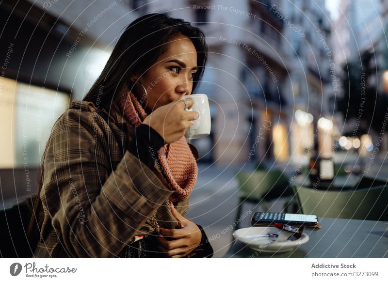 Asiatin genießt Heißgetränk in Straßencafé Frau Café trinken Abend Großstadt urban schlürfen Tasse ethnisch jung stylisch trendy Kaffee Tee Getränk heiß