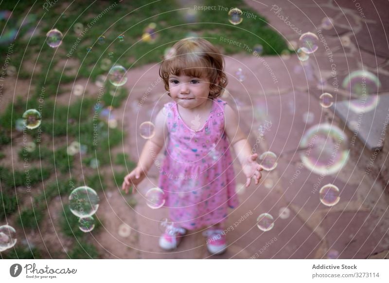 Fröhliches Mädchen spielt mit bunten Blasen im Gras Seife Kindheit freudig Spaß bezaubernd Spielen heiter Park spielerisch Genuss Aktion nass wenig Bewegung