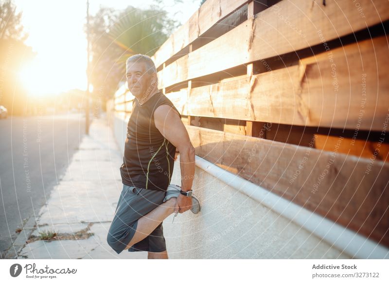 Älterer Mann streckt sich auf Holzwand in Straße strecken sportlich älter Wand reif alt Form Training Läufer Athlet Fitness Großstadt passen Gesundheit Übung